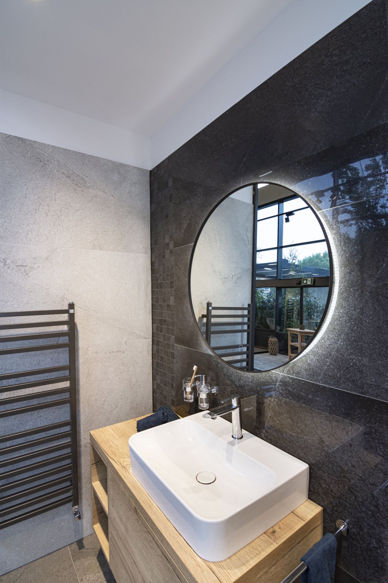 Vzorová koupelna s elegantním kruhovým zrcadlem a sanitou